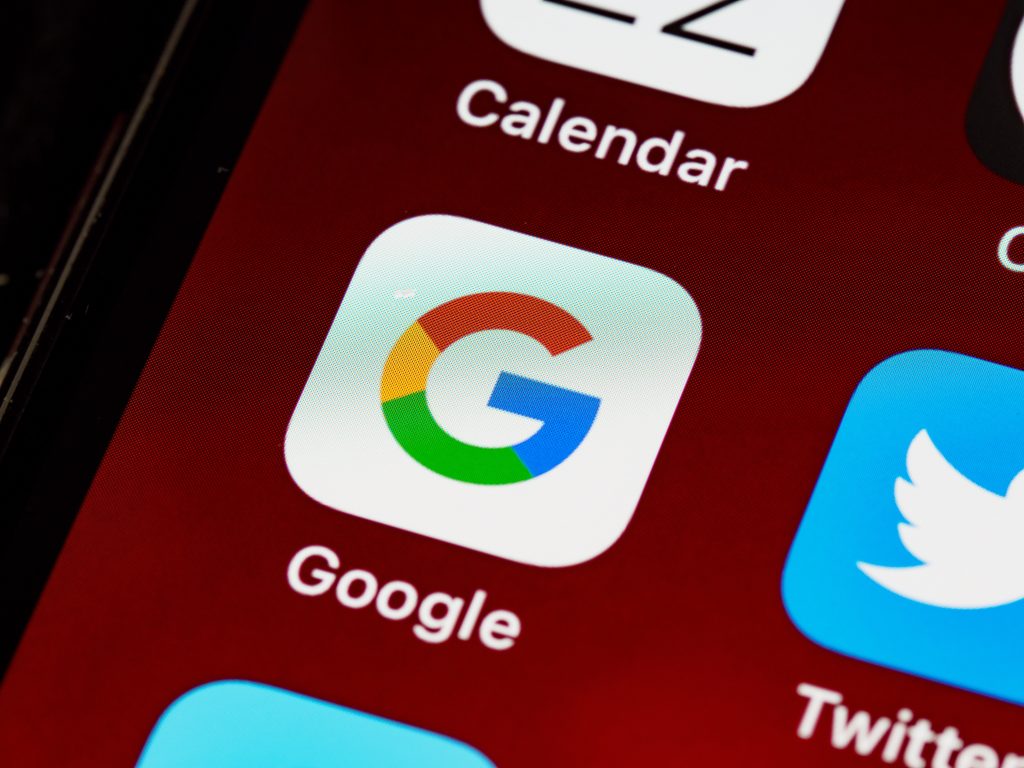 A tela de um celular com o plano de fundo vermelho, focando no ícone do Google